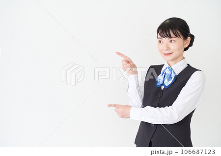 指で指し示すベストにリボンタイの制服を着た、受付業務、事務業務の女性 指で指し示すベストにリボンタイの制服を着た、受付業務、事務業務の女性 106687123