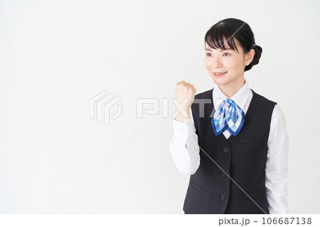 ガッツポーズをするベストにリボンタイの制服を着た、受付業務、事務業務の女性 ガッツポーズをするベストにリボンタイの制服を着た、受付業務、事務業務の女性 106687138