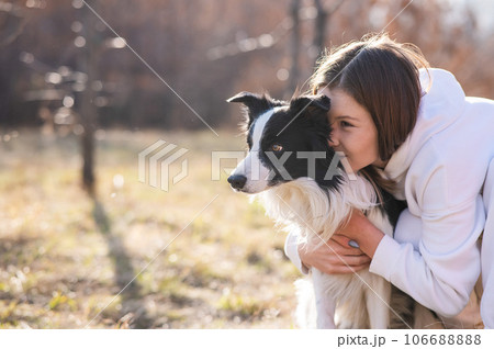 Caucasian woman hugging her dog Border Collie while sitting on a bench in autumn park. Caucasian woman hugging her dog Border Collie while sitting on a bench in autumn park. 106688888