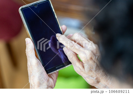一生懸命スマホを操作している高齢女性の手元 106689211