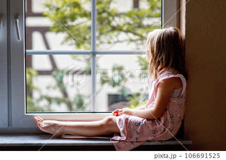 Adorable little girl sitting by the window. preschool child looking out and dreaming. Adorable little girl sitting by the window. preschool child looking out and dreaming. 106691525