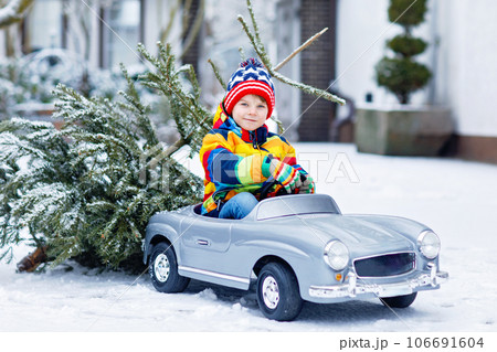 Funny little smiling kid boy driving toy car with Christmas tree. Funny little smiling kid boy driving toy car with Christmas tree. 106691604