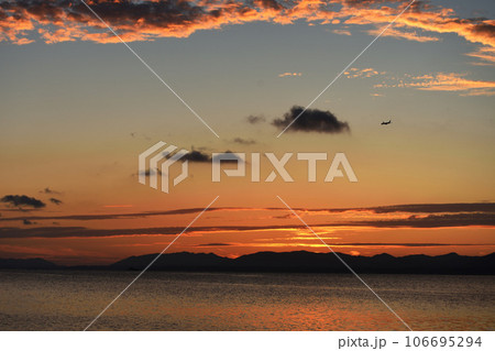 海に沈む夕日と飛行機 106695294