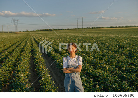 Smiling female farmer with crossed hands standing on potato field background. Agriculture concept 106696390
