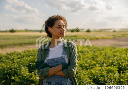 Woman agronomist with crossed hands standing on potato field background. Agriculture concept Woman agronomist with crossed hands standing on potato field background. Agriculture concept 106696396