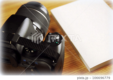 木目のテーブルに置かれたカメラと冊子(イラスト風) 木目のテーブルに置かれたカメラと冊子(イラスト風) 106696779