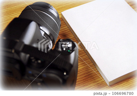 木目のテーブルに置かれたカメラと冊子（イラスト風） 106696780