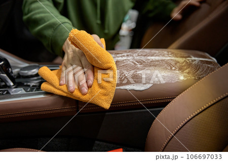 Closeup car detailing studio worker cleaning leather interior 106697033