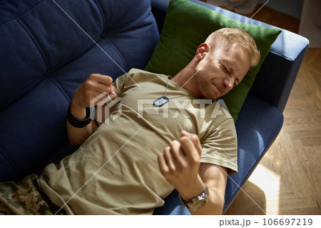 Military man frowning face lying on couch felling lost despair Military man frowning face lying on couch felling lost despair 106697219