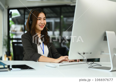 Attractive female customer service representatives wearing headset working on support hotline in modern workplace 106697677
