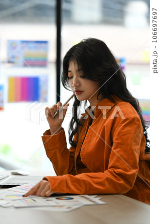 Thoughtful young female creative designer thinking, solving problem and review project at her workplace 106697697