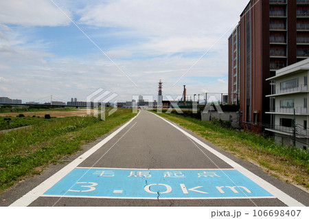 大阪工業大学大宮キャンパスの建物近くの淀川堤防の舗装道路に示された毛馬起点3.0kmの文字 106698407