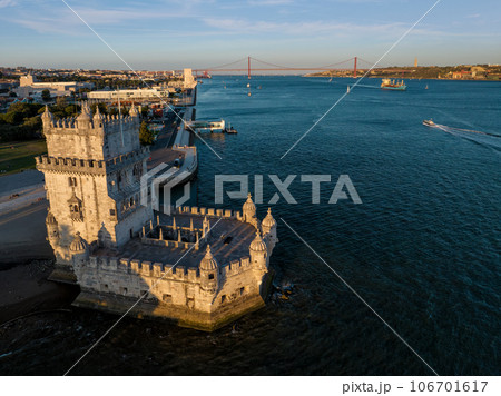 Aerial view of Belem Tower famous tourist landmark of Lisboa and tourism attraction on the bank of the Tagus River (Tejo) with tourist boat and cargo container ship at sunset. Lisbon, Portugal Aerial view of Belem Tower famous tourist landmark of Lisboa and tourism attraction on the bank of the Tagus River (Tejo) with tourist boat and cargo container ship at sunset. Lisbon, Portugal 106701617