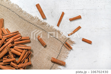 Tabletop view - Heap of cinnamon bark sticks on linen tablecloth and white stone desk Tabletop view - Heap of cinnamon bark sticks on linen tablecloth and white stone desk 106702430