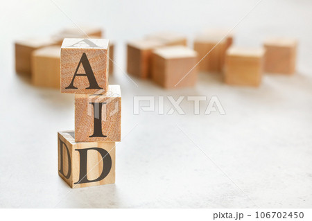 Three wooden cubes with word AID, on white table, more in background, space for text in right down corner Three wooden cubes with word AID, on white table, more in background, space for text in right down corner 106702450