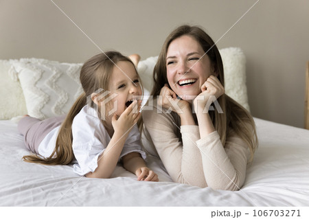Cheerful caring mom lying at kid on double bed Cheerful caring mom lying at kid on double bed 106703271