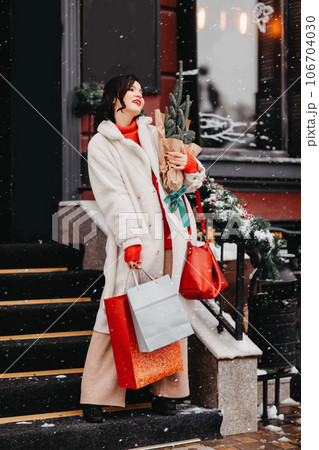 beautiful brunette on the stairs with shopping and a Christmas tree. winter city beautiful brunette on the stairs with shopping and a Christmas tree. winter city 106704030