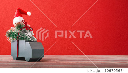 Christmas greeting card.grreen car carry pine tree with presents ribbon on red background table Christmas greeting card.grreen car carry pine tree with presents ribbon on red background table 106705674