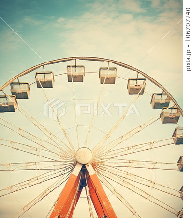an old ferris wheel with blue sky and clouds in the background, taken on a vintage film camera stock photo an old ferris wheel with blue sky and clouds in the background, taken on a vintage film camera stock photo 106707240
