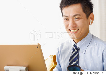 タブレット端末を見ながら食事をする男性 106708453