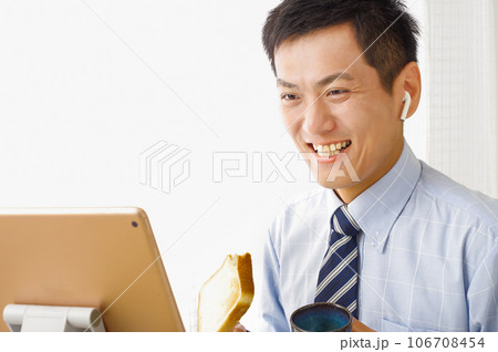タブレット端末を見ながら食事をする男性 タブレット端末を見ながら食事をする男性 106708454