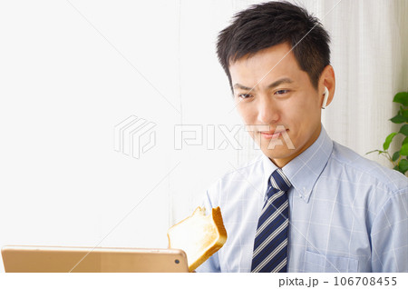 タブレット端末を見ながら食事をする男性 106708455
