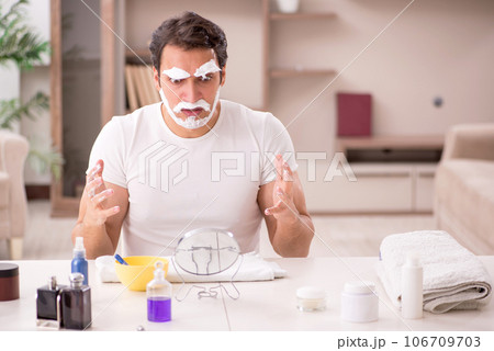 Young man shaving face at home 106709703