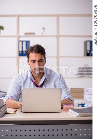 Young male employee and too much work in the office Young male employee and too much work in the office 106709866