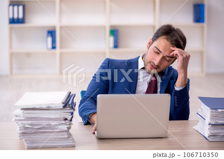Young male employee and too much work in the office Young male employee and too much work in the office 106710350