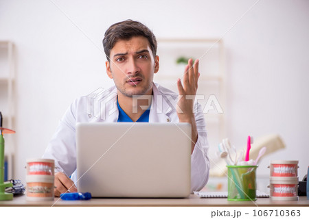 Young male dentist working in the clinic 106710363