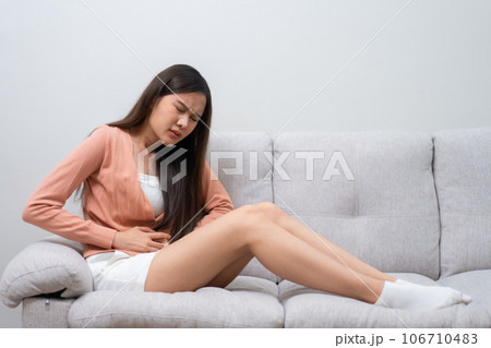 Sick Asian Woman Suffering From Acute Abdominal Pain in the abdomen due to menstruation period, PMS. Sitting On Couch, stomachache from food poisoning, abdominal pain, digestive problem, gastritis Sick Asian Woman Suffering From Acute Abdominal Pain in the abdomen due to menstruation period, PMS. Sitting On Couch, stomachache from food poisoning, abdominal pain, digestive problem, gastritis 106710483