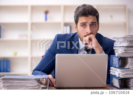 Young male employee and too much work in the office 106710816