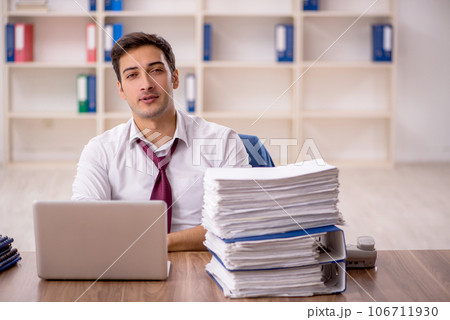 Young male employee and too much work in the office Young male employee and too much work in the office 106711930