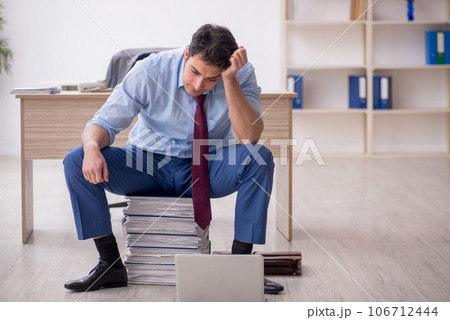 Young male employee unhappy with excessive work in the office 106712444