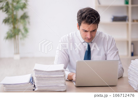 Young male employee and too much work in the office Young male employee and too much work in the office 106712476