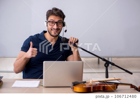 Young male music teacher sitting in the classroom Young male music teacher sitting in the classroom 106712480