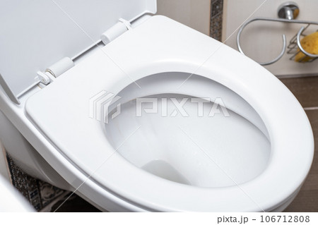 White toilet bowl in the toilet in the bathroom. The toilet before it is washed. The concept of cleaning and cleanliness. White toilet bowl in the toilet in the bathroom. The toilet before it is washed. The concept of cleaning and cleanliness. 106712808