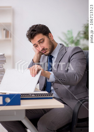Young male employee and too much work in the office 106713523