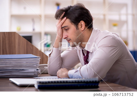 Young male employee and too much work in the office 106713752