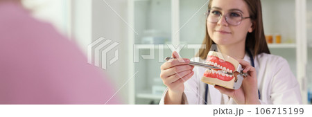 Young woman dentist explains rules of dental care to her patient. Young woman dentist explains rules of dental care to her patient. 106715199