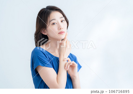 木漏れ日の白バックでスキンケアをする若い女性 木漏れ日の白バックでスキンケアをする若い女性 106716895
