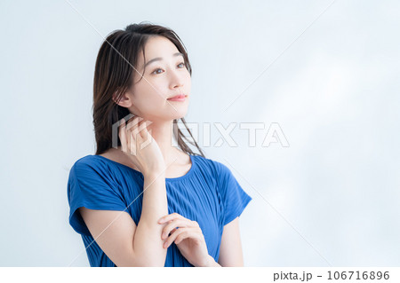木漏れ日の白バックでスキンケアをする若い女性 木漏れ日の白バックでスキンケアをする若い女性 106716896
