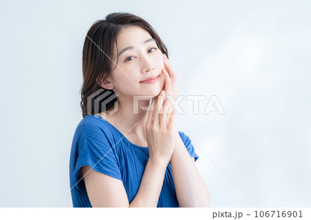 木漏れ日の白バックでスキンケアをする若い女性 106716901
