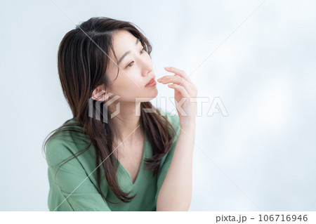 木漏れ日の白バックでスキンケアをする若い女性 木漏れ日の白バックでスキンケアをする若い女性 106716946