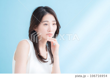 日差しが差し込むブルーバックでスキンケアをする若い女性 日差しが差し込むブルーバックでスキンケアをする若い女性 106716954