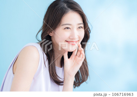 日差しが差し込むブルーバックでスキンケアをする若い女性 日差しが差し込むブルーバックでスキンケアをする若い女性 106716963