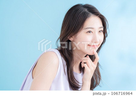 日差しが差し込むブルーバックでスキンケアをする若い女性 日差しが差し込むブルーバックでスキンケアをする若い女性 106716964