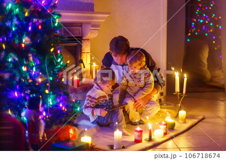 Father and his two little children sitting by fireplace chimney on Christmas Eve time. Father and his two little children sitting by fireplace chimney on Christmas Eve time. 106718674