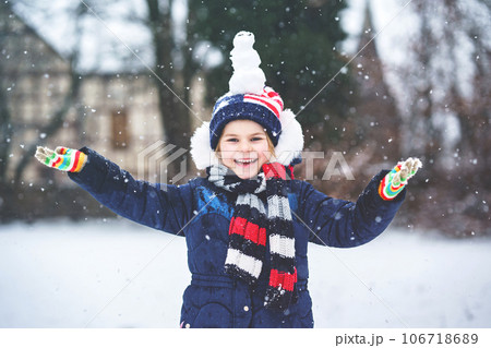 Cute little preschool girl with mini snowman on head. Adorable healthy happy child playing and having fun with snow, outdoors on cold day. Active leisure with children in winter 106718689