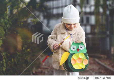 Little preschool kid girl holding selfmade traditional owl lanterns with candle for St. Martin procession. child happy about children and family parade in kindergarten. German tradition Martinsumzug 106718706
